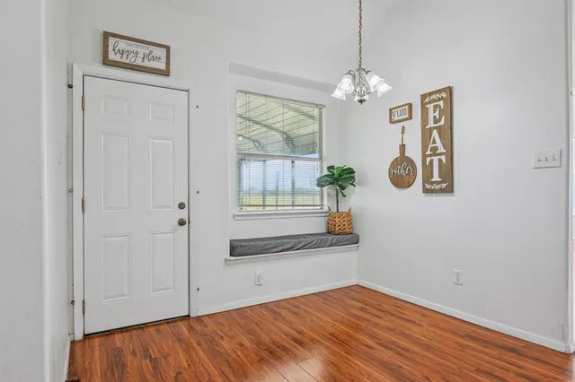 a view of an empty room with chandelier and wooden floor