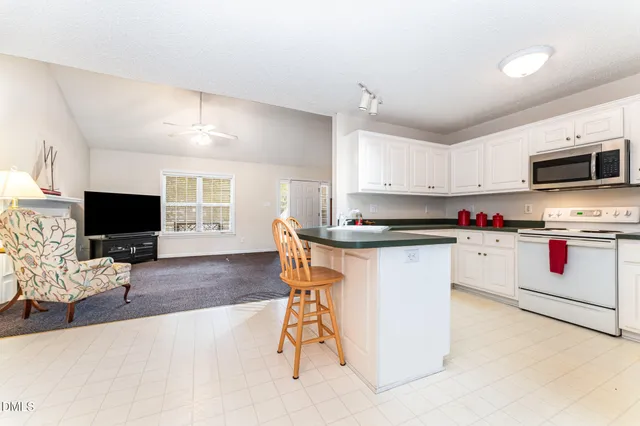 a kitchen with stainless steel appliances kitchen island granite countertop a stove top oven a sink dishwasher and a microwave oven on the blue kitchen countertops with a flat screen tv