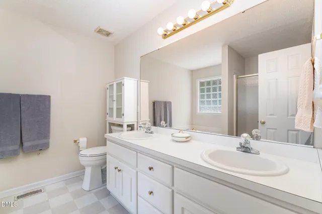 a bathroom with a double vanity sink toilet and a mirror