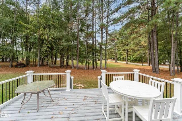 a view of a patio with table and chairs with wooden floor and fence