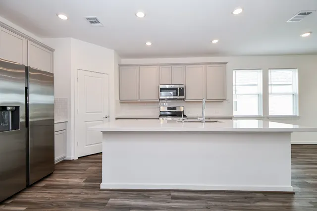 a kitchen with stainless steel appliances granite countertop a refrigerator a sink and white cabinets