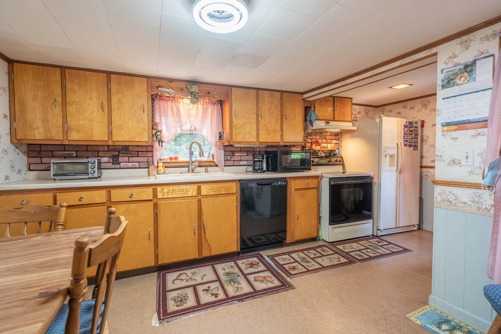 607 Podunk Road East Brookfield, MA 01515 - Photo 23 of 42 a kitchen with stainless steel appliances a stove a sink cabinets and a window
