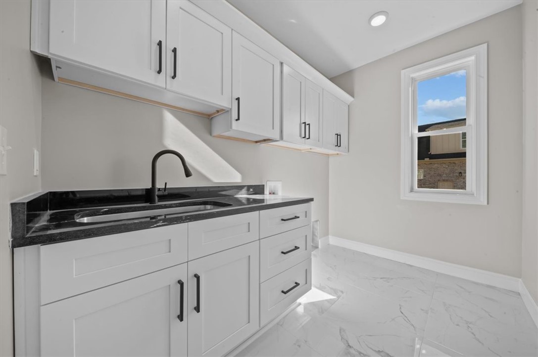 105 Bree Drive Anderson, SC 29621 - Photo 39 of 48 A well-appointed laundry space features sleek cabinetry, dark countertops, and bright flooring, creating an inviting atmosphere.