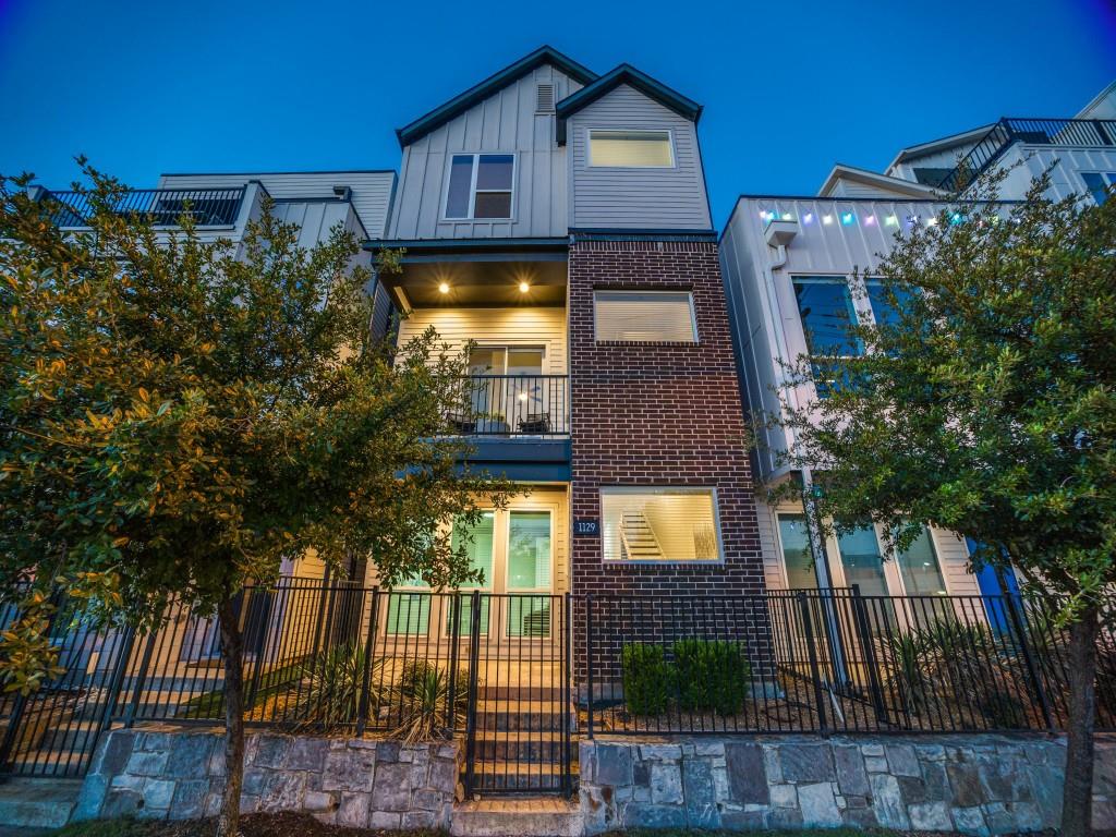 1129 Manderly Court Dallas, TX 75204 - Photo 1 of 33 View of front facade with a balcony, brick siding, a fenced front yard, and board and batten siding