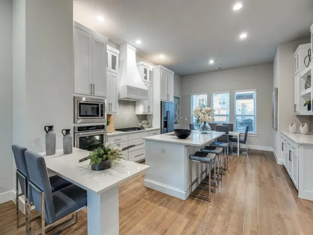 a kitchen with a dining table chairs stove microwave and cabinets