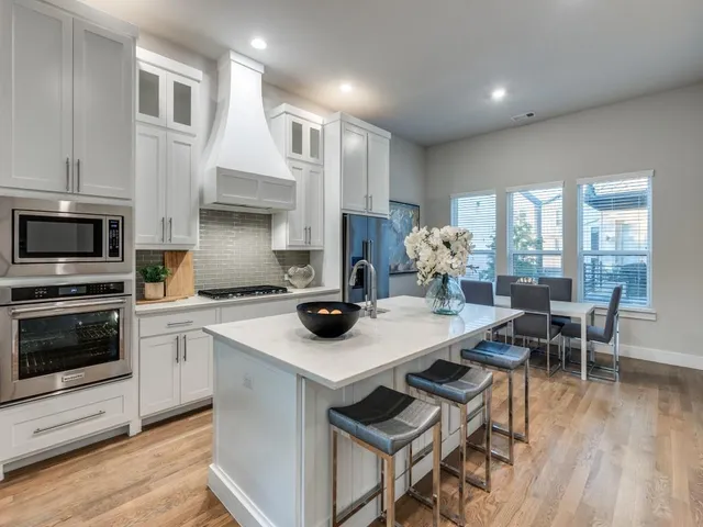a kitchen with a stove a refrigerator and a dining table with wooden floor