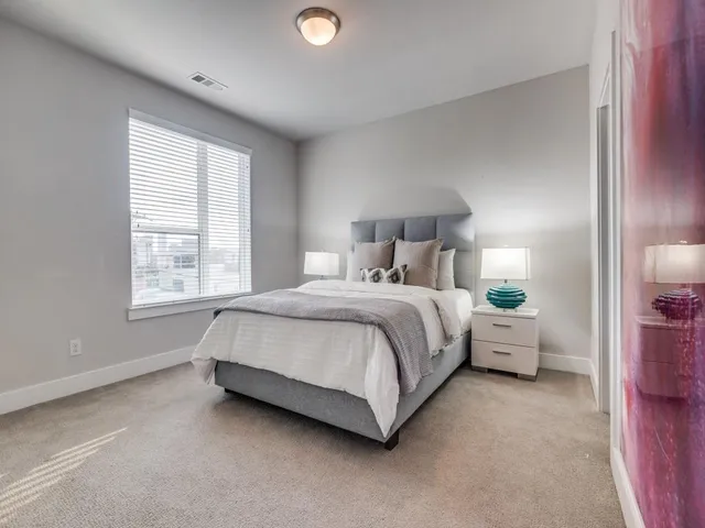 a spacious bedroom with a bed and a lamp