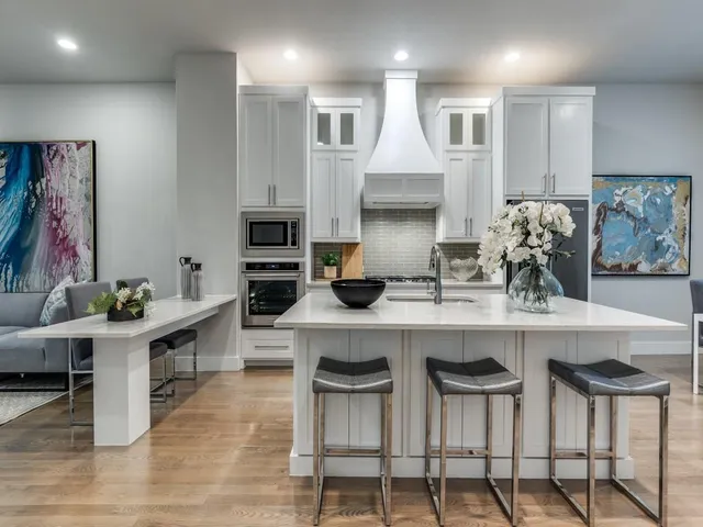 a kitchen with stainless steel appliances granite countertop a table chairs sink and cabinets