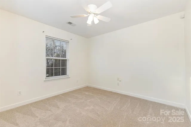an empty room with a window and a fan