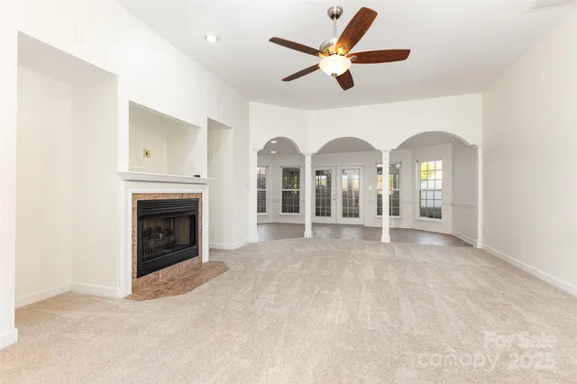 a view of a livingroom with a fireplace a ceiling fan and wooden floor