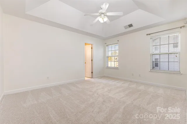an empty room with windows and ceiling fan