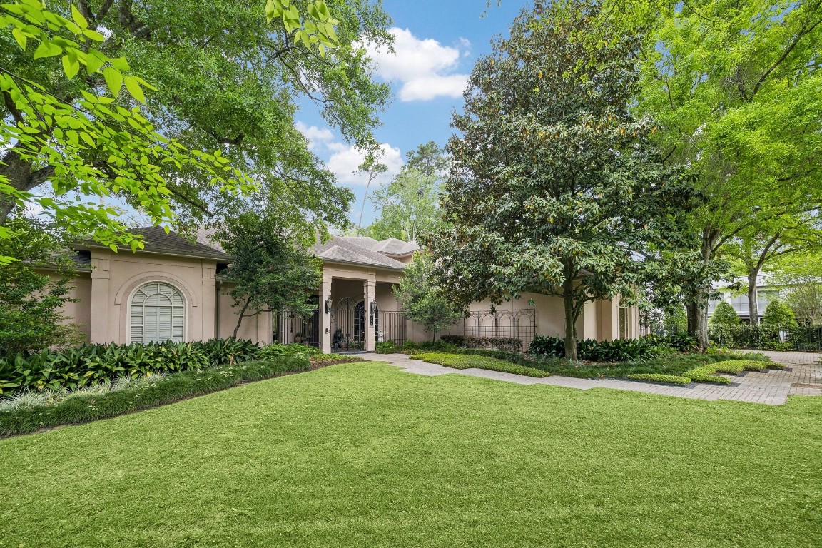 Beautifully landscaped front yard with mature trees and lush greenery framing this stunning home.  An inviting walkway leads to a private, gated courtyard offering both curb appeal and sense of seclusion.