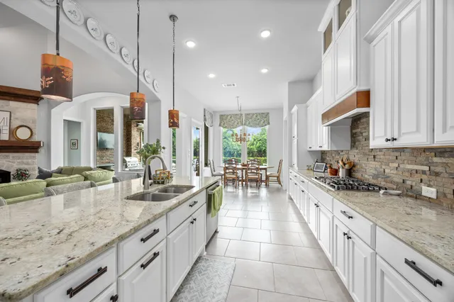 a large kitchen with granite countertop a sink and cabinets