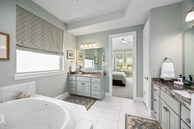 a en suite bathroom with a granite countertop sink mirror and a bathtub