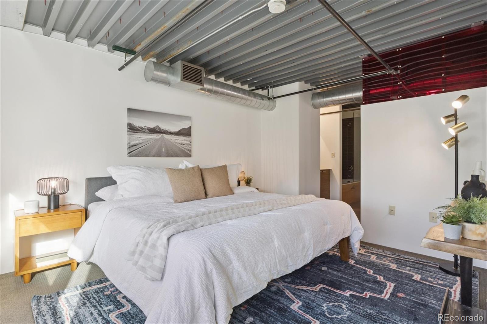 3457 Ringsby Court, Unit 320 Denver, CO 80216 - Photo 12 of 41 a bedroom with bed and wooden floor