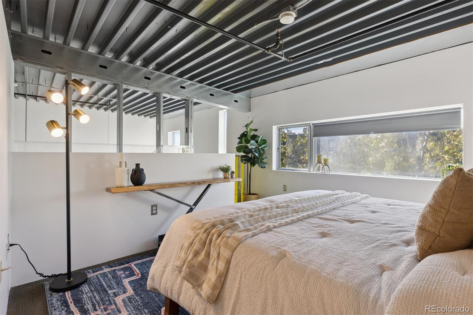 3457 Ringsby Court, Unit 320 Denver, CO 80216 - Photo 14 of 41 a bed sitting in a room next to a window