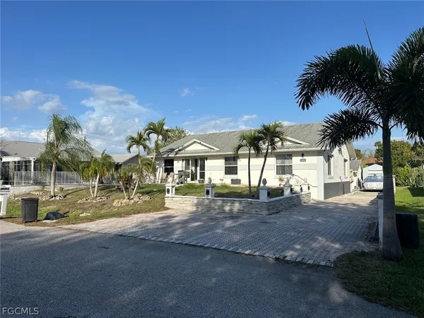 a view of a house with a yard and palm trees