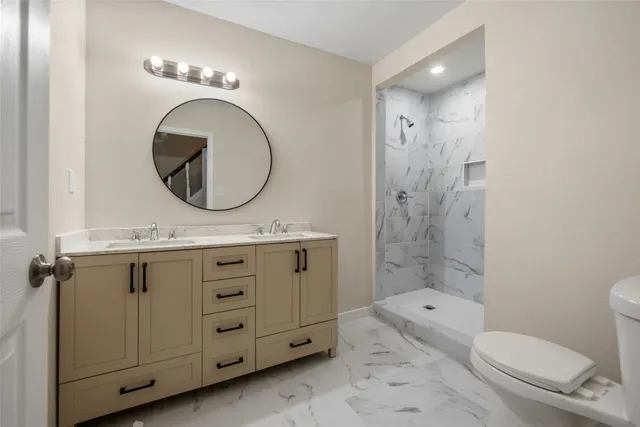a bathroom with a granite countertop toilet a sink and a mirror