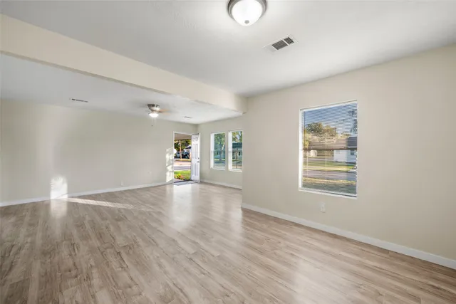 an empty room with wooden floor and windows