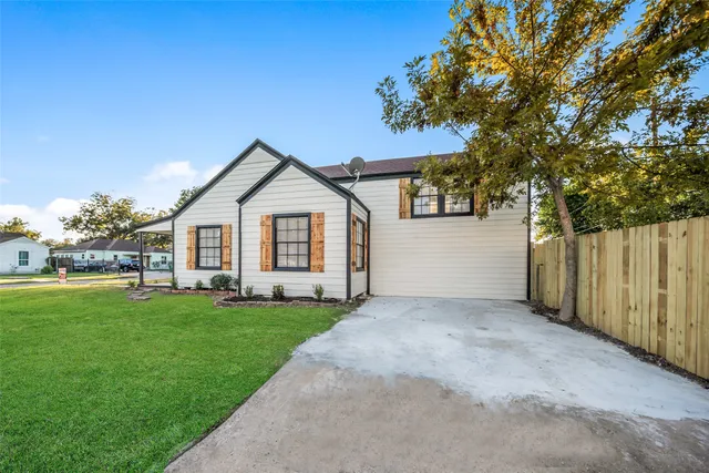 a view of a yard in front of a house with plants and large tree