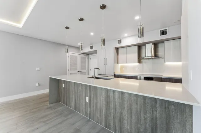 a large kitchen with stainless steel appliances a large counter top a stove and a sink