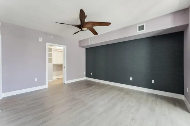 an empty room with wooden floor cabinet and windows