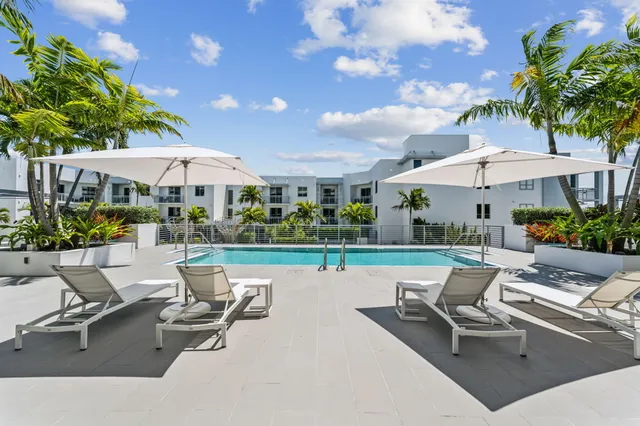 a view of a patio with a table and chairs under an umbrella with a fire pit and potted plants