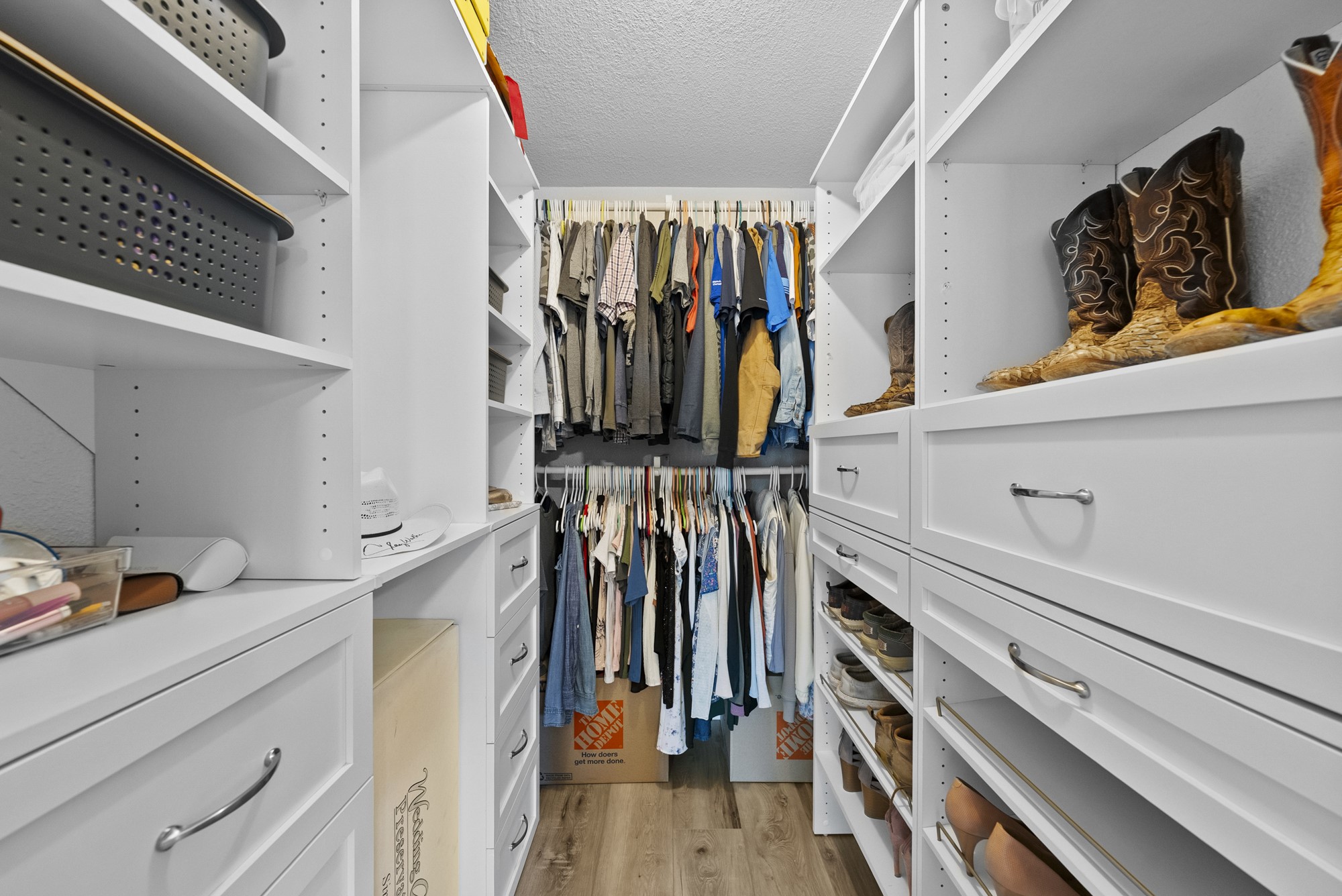 2802 Robin Road Manchaca, TX 78652 - Photo 33 of 40 Custom closet system featuring white cabinetry, varied shelving, multiple hanging rods, built-in shoe storage, and wood-finish flooring
