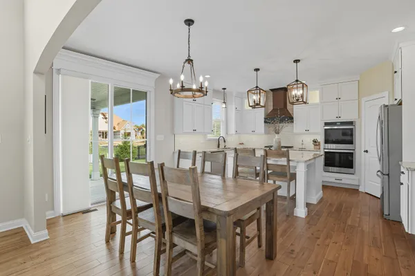 a view of a dining room and livingroom with furniture wooden floor a chandelier