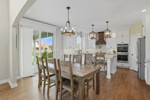 a view of a dining room and livingroom with furniture wooden floor a chandelier