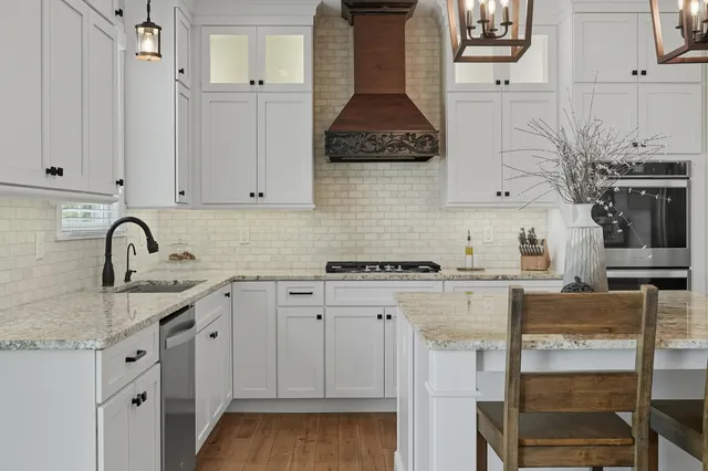 a kitchen with stainless steel appliances granite countertop a stove a sink and white cabinets