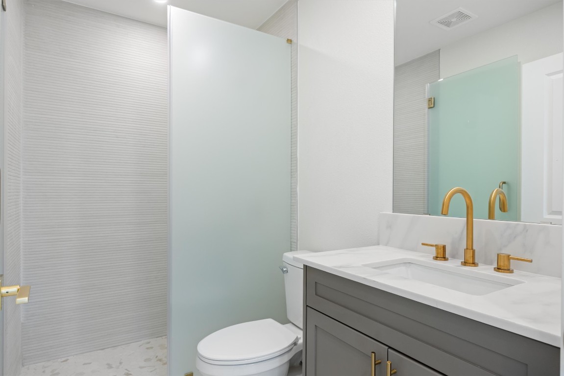 109 Fall Drive Georgetown, TX 78633 - Photo 5 of 40 a bathroom with a granite countertop toilet a sink and a mirror