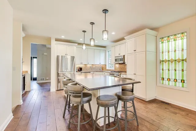 a kitchen with stainless steel appliances a dining table chairs refrigerator and sink