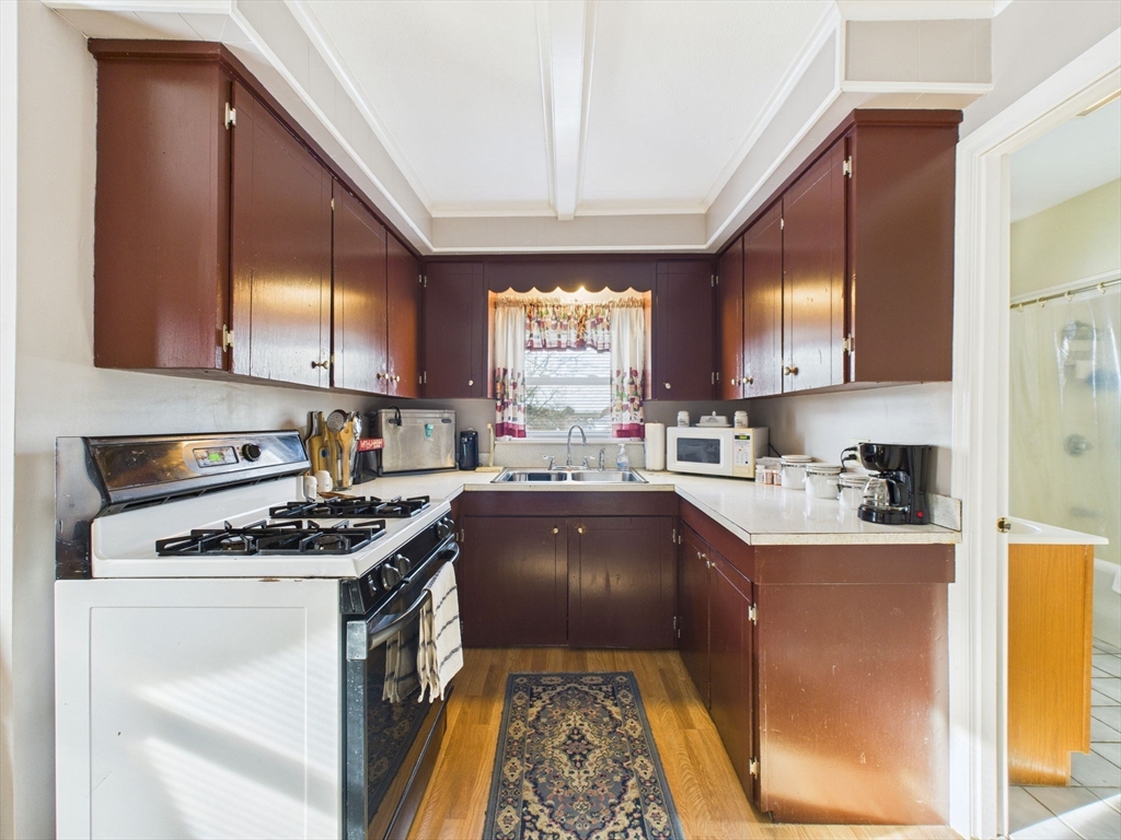 371 Reed Street New Bedford, MA 02740 - Photo 30 of 42 a kitchen with kitchen island granite countertop a stove a sink and a microwave