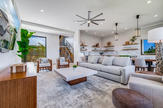 a living room with furniture kitchen view and a large window