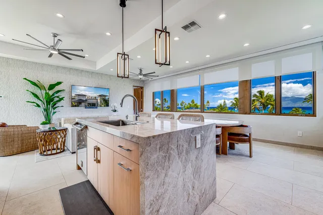 a kitchen with stainless steel appliances kitchen island a large counter top a sink a stove a dining table and chairs