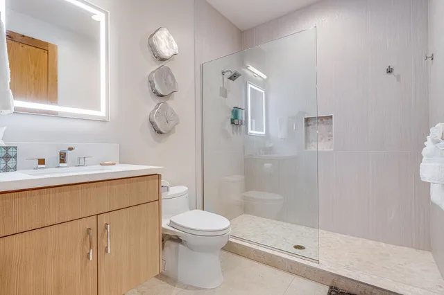 a bathroom with a shower sink mirror and toilet