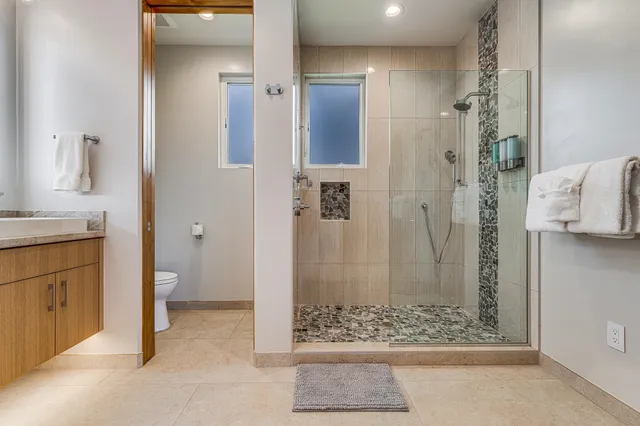 a bathroom with a granite countertop shower a sink and a mirror