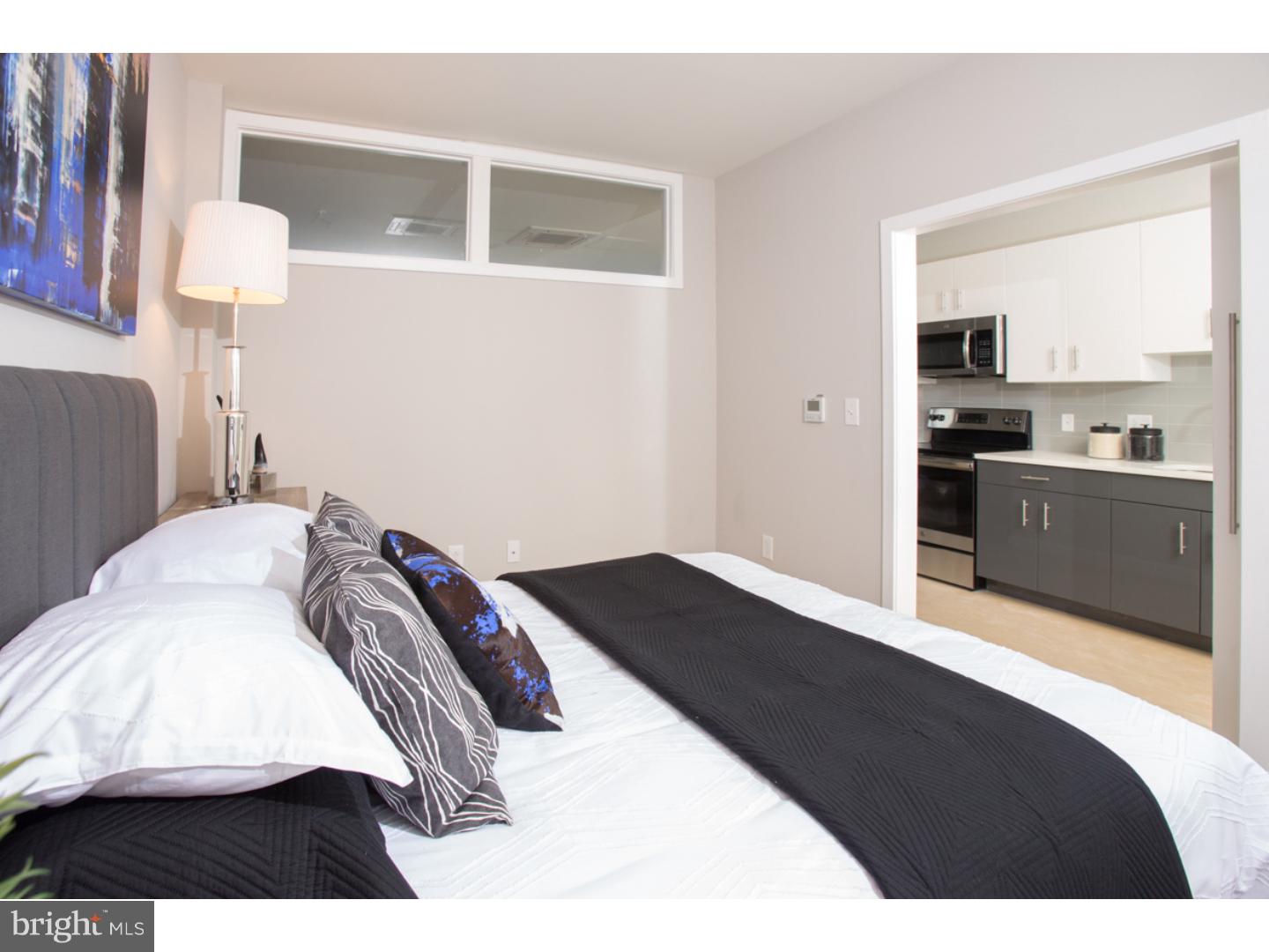 121 North 2nd Street, Unit 214 Philadelphia, PA 19106 - Photo 12 of 17 a bedroom with a bed and lamp on dresser