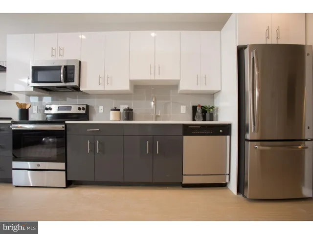 a kitchen with stainless steel appliances a sink a stove a refrigerator cabinets and a window