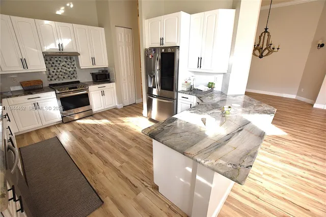 a view of a kitchen with kitchen island stainless steel appliances a sink stove and living room view