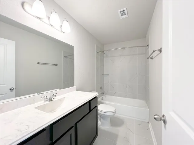 a bathroom with a granite countertop sink a toilet and shower