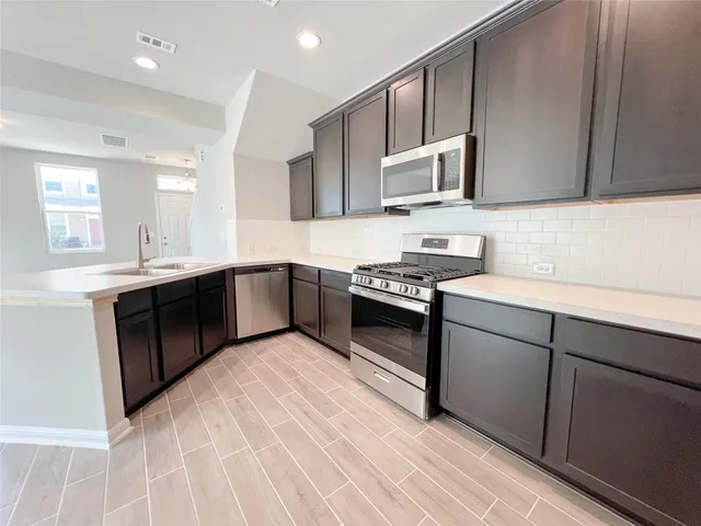 a kitchen with stainless steel appliances granite countertop a stove a sink and a microwave