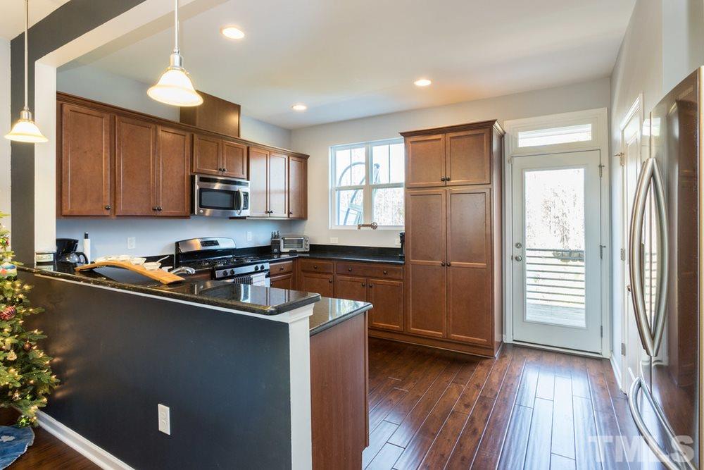 1619 Crafton Way Raleigh, NC 27607 - Photo 12 of 25 a kitchen with stainless steel appliances granite countertop a refrigerator a sink a stove a microwave and wooden floors