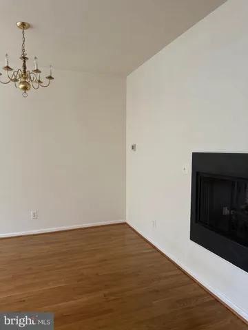 a view of an empty room with wooden floor and a fireplace