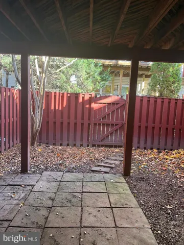 a view of a backyard with large trees and wooden fence