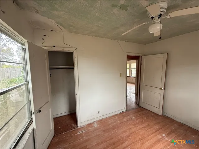 a view of empty room with wooden floor and fan