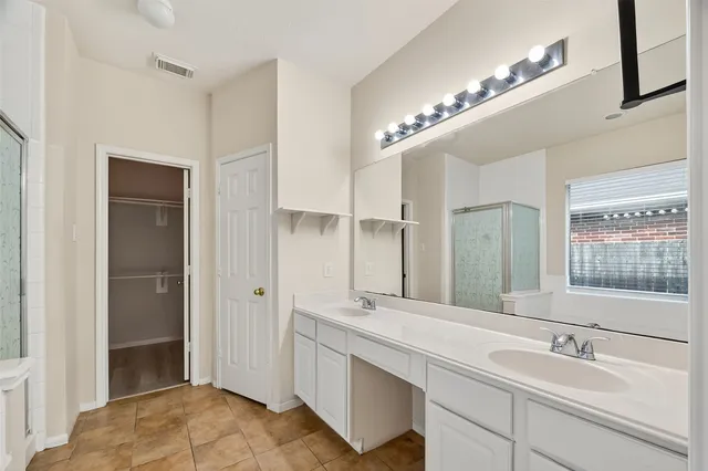 a bathroom with a double vanity sink a large mirror and a shower