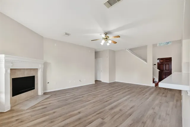 a view of an empty room with wooden floor and fireplace