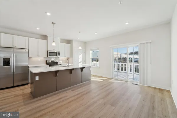 a kitchen with stainless steel appliances granite countertop a refrigerator a sink dishwasher a stove and white cabinets with wooden floor